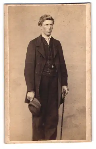Fotografie unbekannter Fotograf und Ort, junger Mann im dunklen Anzug mit Flanierstock und Schirmmütze