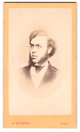 Fotografie W. Rottmann, Wien, Portrait junger Mann im Anzug mit Backenbart und Brille, 1873