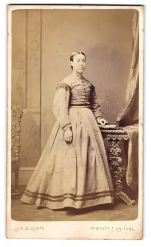 Fotografie A. D. Lewis, Newcastle upon Tyne, junge Engländerin im hellen Kleid stehend am Schreibtisch