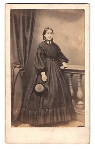 Fotografie H. Pickering, Scarborough, junge Dame im schwarzen Biedermeierkleid mit Hut in der Hand