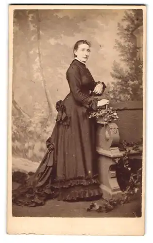 Fotografie Stuart Brothers, London, junge Dame im dunklen Kleid posiert stehend an einer Bank