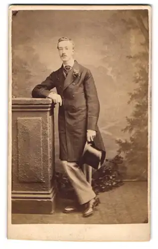 Fotografie Stuart Brothers, London, junger Mann im Anzug mit Mantel und Zylinder in der Hand