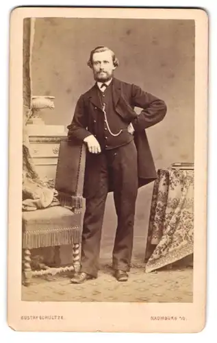 Fotografie Gustav Schultze, Naumburg / Saale, Herr im dunklen Anzug mit Uhrenkette posiert im Atelier