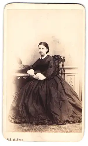 Fotografie R. Eich, Dresden, junge Sächsin im schwarzen Reifrockkleid sitzend im Atelier