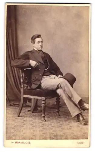 Fotografie W. Monkhouse, York, junger Engländer im Anzug mit Hut sitzt lässig im Stuhl