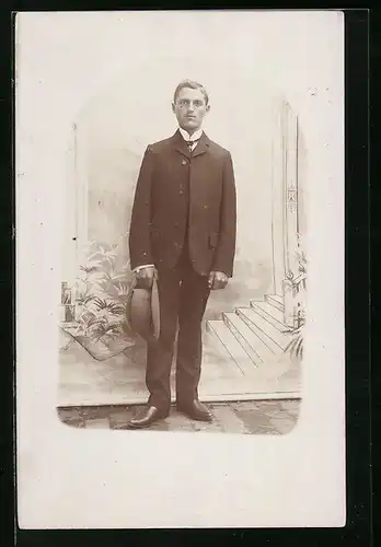 Foto-AK Junger Mann mit Hut in der Hand vor gezeichneter Treppenhaus-Kulisse, Passepartout