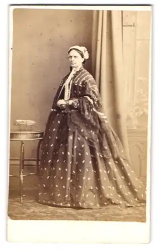 Fotografie Sturat, Helensburgh, schottische Dame im gemusterten Kleid mit Haube stehend im Atelier