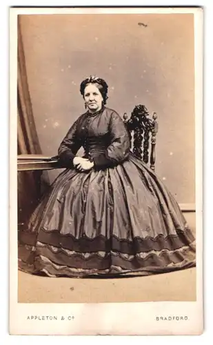 Fotografie Appleton & Co., Bradford, ältere englische Dame im dunklen Reifrockkleid mit Haube und Ohrringen