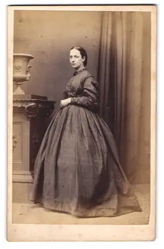 Fotografie M. Boak, Driffield, Dame im schlichten Reifrockkleid mit Brosche