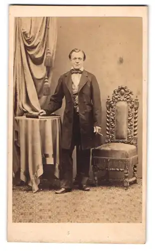 Fotografie C. T. Schultze, Querfurt, junger Mann im dunklen Anzug mit Fliege posiert rauchend im Atelier