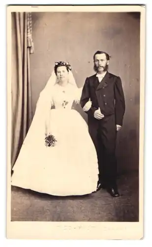 Fotografie unbekannter Fotograf und Ort, Brautpaar im Hochzeitskleid und im dunklen Frack mit Backenbart