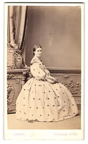 Fotografie J. Hawke, Devon, hübsche junge Engländerin im gemusterten Kleid mit posiert sitzend im Atelier