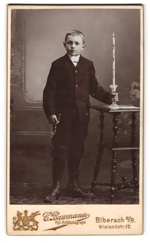 Fotografie C. Baumann, Biberach a. R., junger Knabe im Anzug mit Kommunionskerze und Rosenkranz