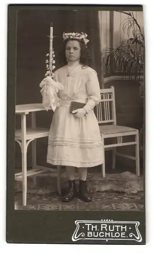Fotografie Th. Ruth, Buchloe, Mädchen mit Kommunionskerze im weissen Kleid, Haarschmuck
