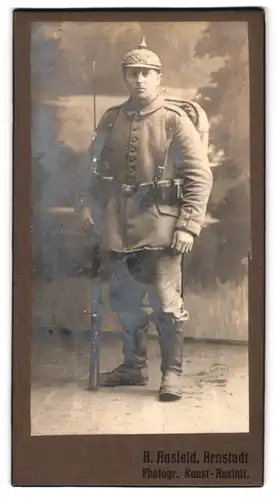 Fotografie A. Ausfeld, Arnstadt, Soldat in Feldgrau Uniform mit Ersatz Pickelhaube Metall und Ausmarschgepäck, Affe