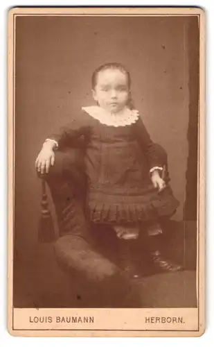 Fotografie Louis Baumann, Herborn, kleines Mädchen im süssen Kleidchen auf einem Sessel stehend