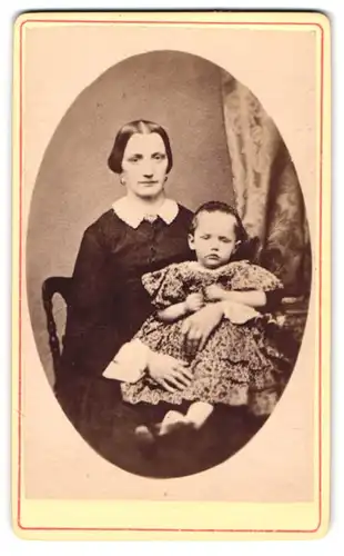 Fotografie unbekannter Fotograf und Ort, Mutter im dunklen Kleid mit Tochter im Blümchenkleid