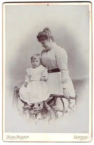Fotografie Carl Bellach, Leipzig, Mutter in gestreifter Bluse mit Tochter im weissen Kleid auf dem Zaun