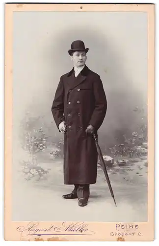 Fotografie August Müller, Peine, junger Mann im Anzug mit Mantel samt Schirm und Melone posiert im Atelier