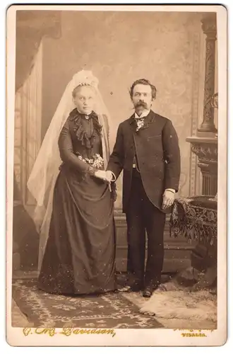 Fotografie Baudson, Ort unbekannt, Eheleute im schwarzen Hochzeitskleid und im Anzug halten Händchen
