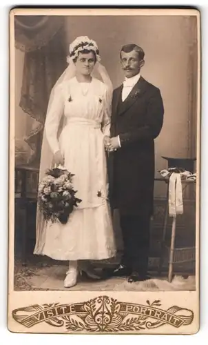 Fotografie unbekannter Fotograf und Ort, Brautpaar im Hochzeitskleid mit Schleier und im Anzug, Zylinder auf dem Tisch