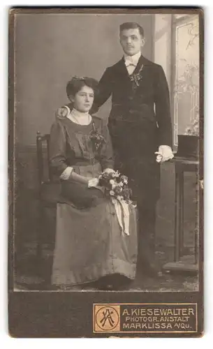 Fotografie A. Kiesewalter, Marklissa, junges polnisches Brautpaar im schlichten Hochzeitskleid und im Anzug mit Zylinder