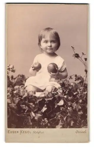 Fotografie Eugen Kegel, Cassel, Gr, Rosenstrasse 5, süsses kleines Mädchen mit Äpfeln in der Hand