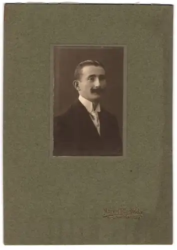 Fotografie Martin Herzfeld, Dresden, Herr im schwarzen Anzug mit Moustache, Trockenstempel 1910