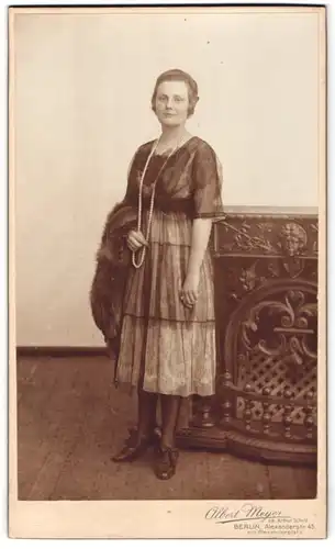 Fotografie Albert Meyer, Berlin, junge Dame im Tüllkleid mit Pelzmantel im Arm und Perlenkette