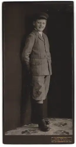 Fotografie Karl Mäckel, Burgstädt i. Sa., grinsender junger Knabe im grauen gestreiften Anzug mit Knickerbockern