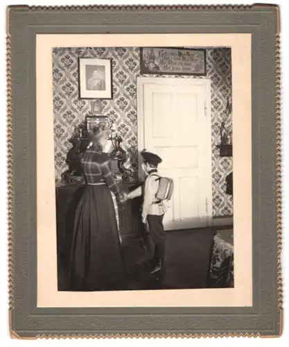 Fotografie unbekannter Fotograf und Ort, Schuljunge verabschiedet sich von seiner Mutter im heimischen Wohnzimmer