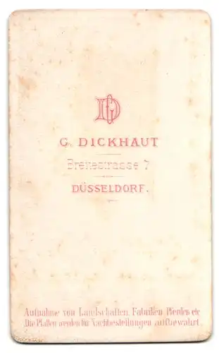 Fotografie G. Dickhaut, Düsseldorf, Soldat in Uniform posiert sitzend im Atelier und zwirbelt seinen Bart
