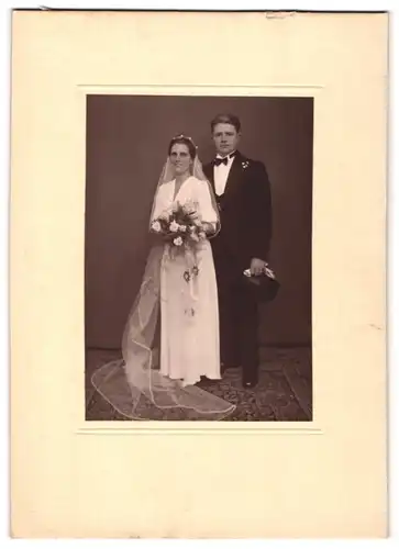 Fotografie unbekannter Fotograf und Ort, Brautpaar im weissen Hochzeitskleid und im Anzug mit Zylinder posieren