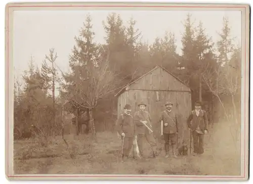 Fotografie unbekannter Fotograf und Ort, vier Jäger mit Jagdhund Dackel und erlegtem Hasen posieren im Wald