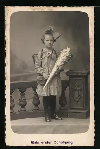 Foto-AK Mädchen mit Zuckertüte und Schleife im Haar zum Schulanfang in Studiokulisse