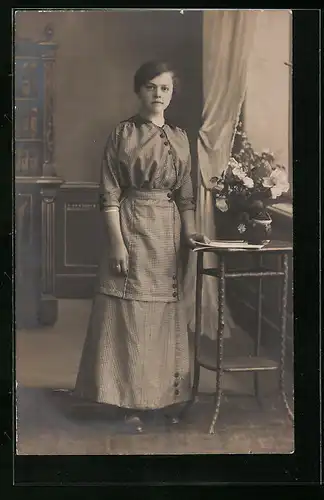 Foto-AK Junge Frau an einem Tischchen vor Studiokulisse