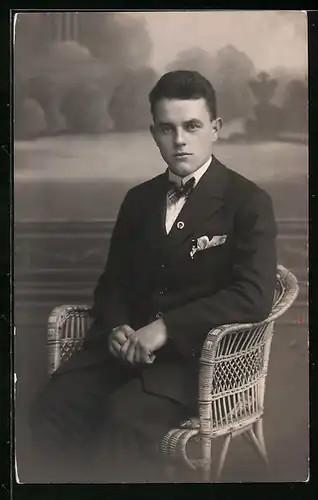 Foto-AK Eleganter junger Mann im Korbsessel vor Studiokulisse