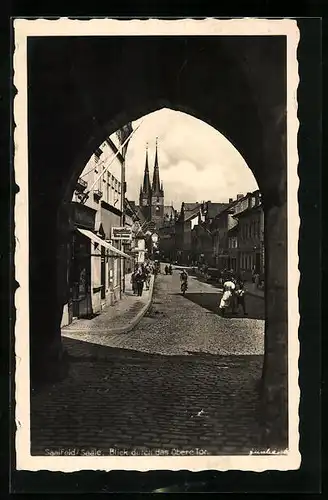 AK Saalfeld /Saale, Strassenpartie mit Geschäften und Kirche durch das Obere Tor