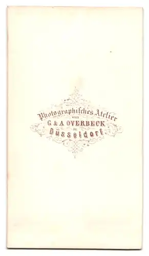 Fotografie G. & A. Overbeck, Düsseldorf, Dame im schulterfreien Kleid mit Halskette und Blumen im Haar