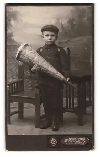 Fotografie M. Scheinfuss, Reichenbach i. V., kleiner Knabe im Anzug mit Zuckertüte und Schulranzen zum ersten Schultag