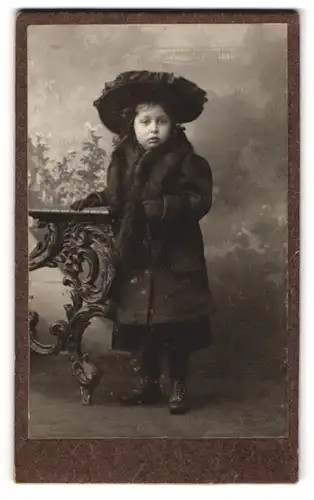 Fotografie unbekannter Fotograf und Ort, kleines Mädchen im dunklen Mantel mit Pelzbesatz und breitem Hut