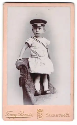 Fotografie Franz Bornee, Saarburg i. Loth., Kleinkind im weissen Kleid als Student mit Couleuer und Schirmmütze