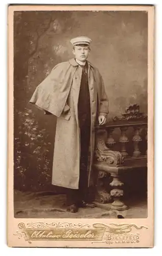 Fotografie Atelier Geisler, Bielefeld, junger Student im Regenmantel mit Tellermütze samt Couleur