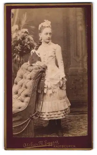 Fotografie M. Eggart, Kaufbeuren, junges Mädchen im weissen Kleid mit langem geflochtenem Zopf, Haarschmuck