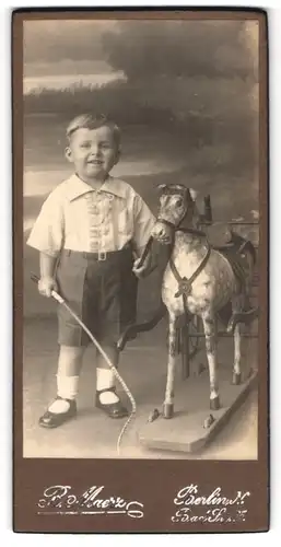Fotografie P. Maerz, Berlin, junger Knabe in kurzen Hosen mit Schaukelpferd und Reitgerte in der Hand