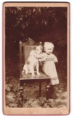 Fotografie unbekannter Fotograf und Ort, niedliches Mädchen im Kleidchen mit ihrem Hund auf dem Stuhl