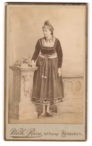 Fotografie Wilh. Risse, Marburg a. L., junge Frau in hessischer Tracht posiert im Atelier