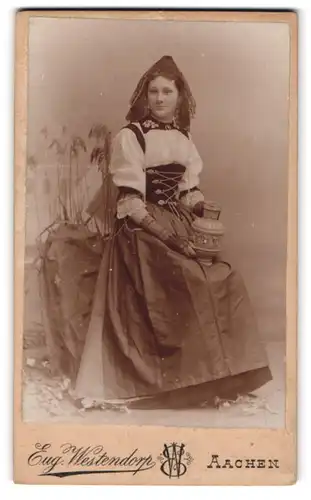 Fotografie Eug. Westendorp, Aachen, junge Frau im Trachtenkleid mit Kopfbedeckung und Amphore