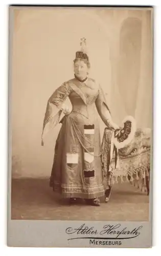 Fotografie Atelier Herrfurth, Merseburg, Dame als Aurora im Kostüm mit Wappen und Fächer mit Aufschrift Civilisation