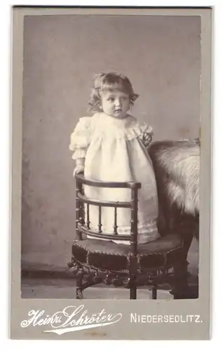 Fotografie Heinr. Schröter, Niedersedlitz, Kleines Mädchen im weissen Kleid steht auf Stuhl